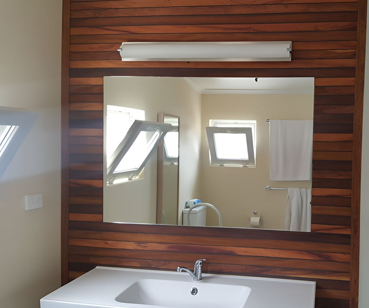 Custom cut-to-size mirror fitted to a timber-clad bathroom wall by All Hours Glass