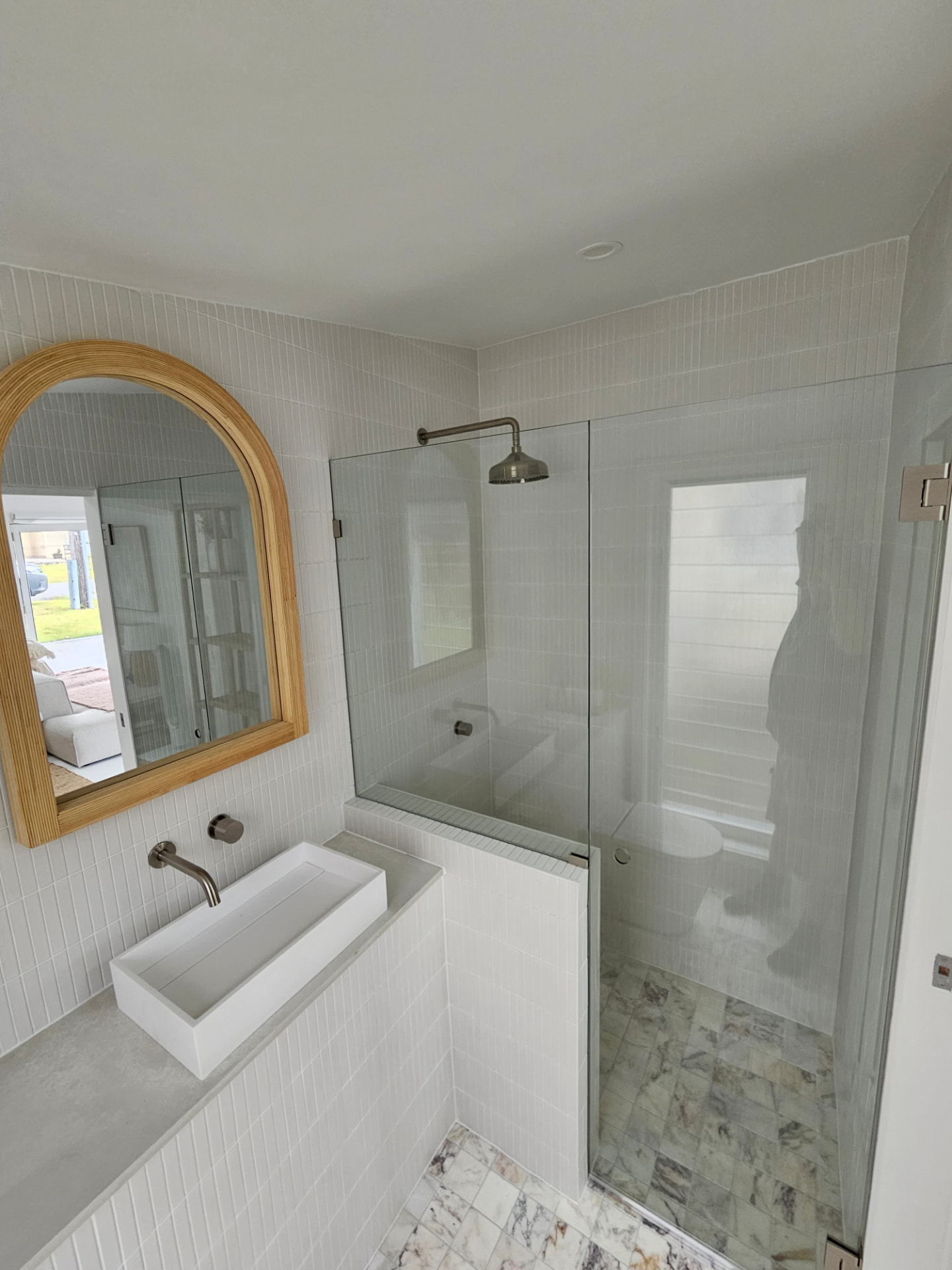 Custom-cut glass shower screen fitted to a compact tiled bathroom